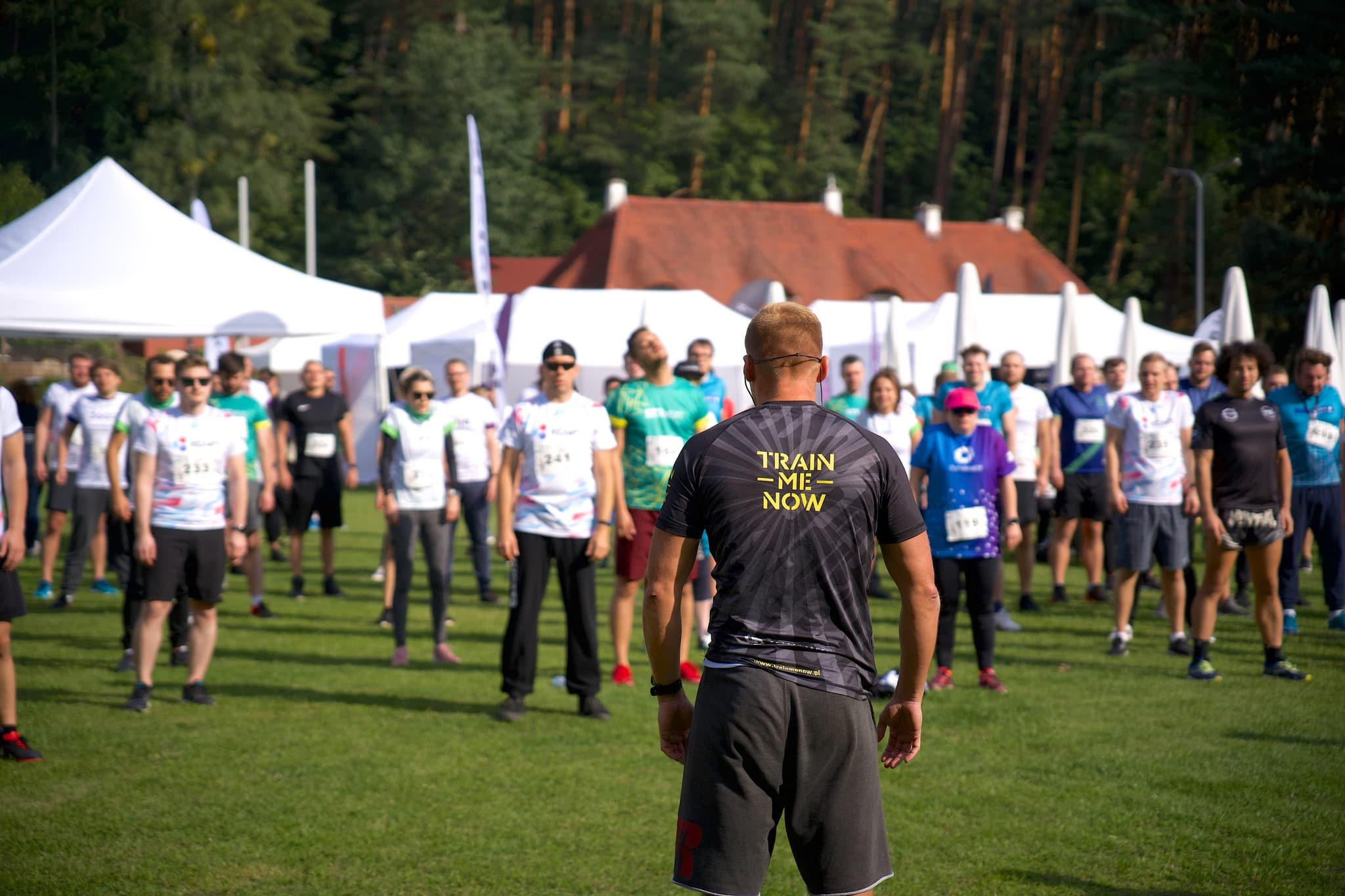 Trener Train Me Now prowadzi rozgrzewkę dla uczestników biegu Olimpiada Just Join IT