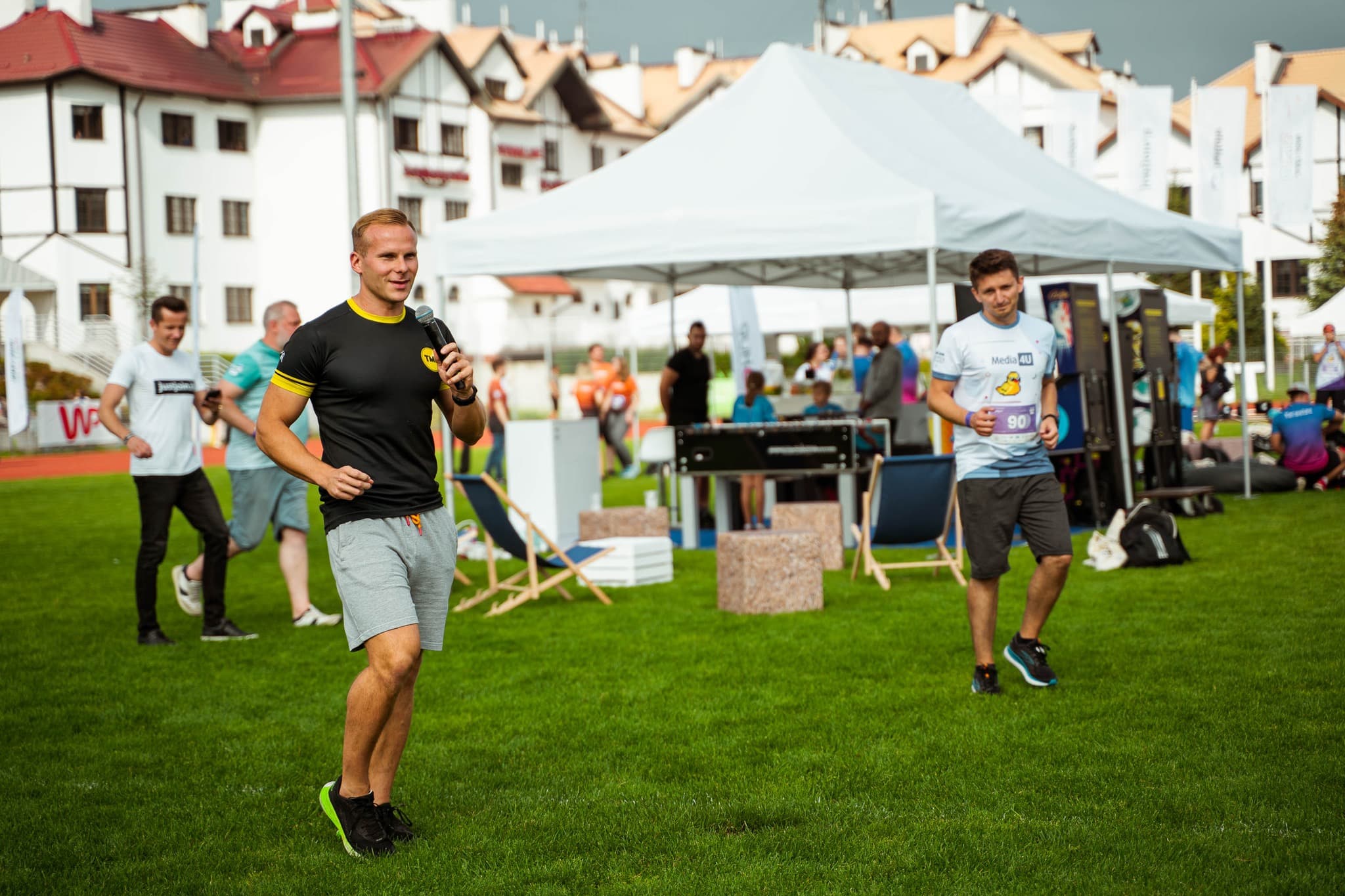 Trener TMN prowadzi event firmowy na świeżym powietrzu z mikrofonem