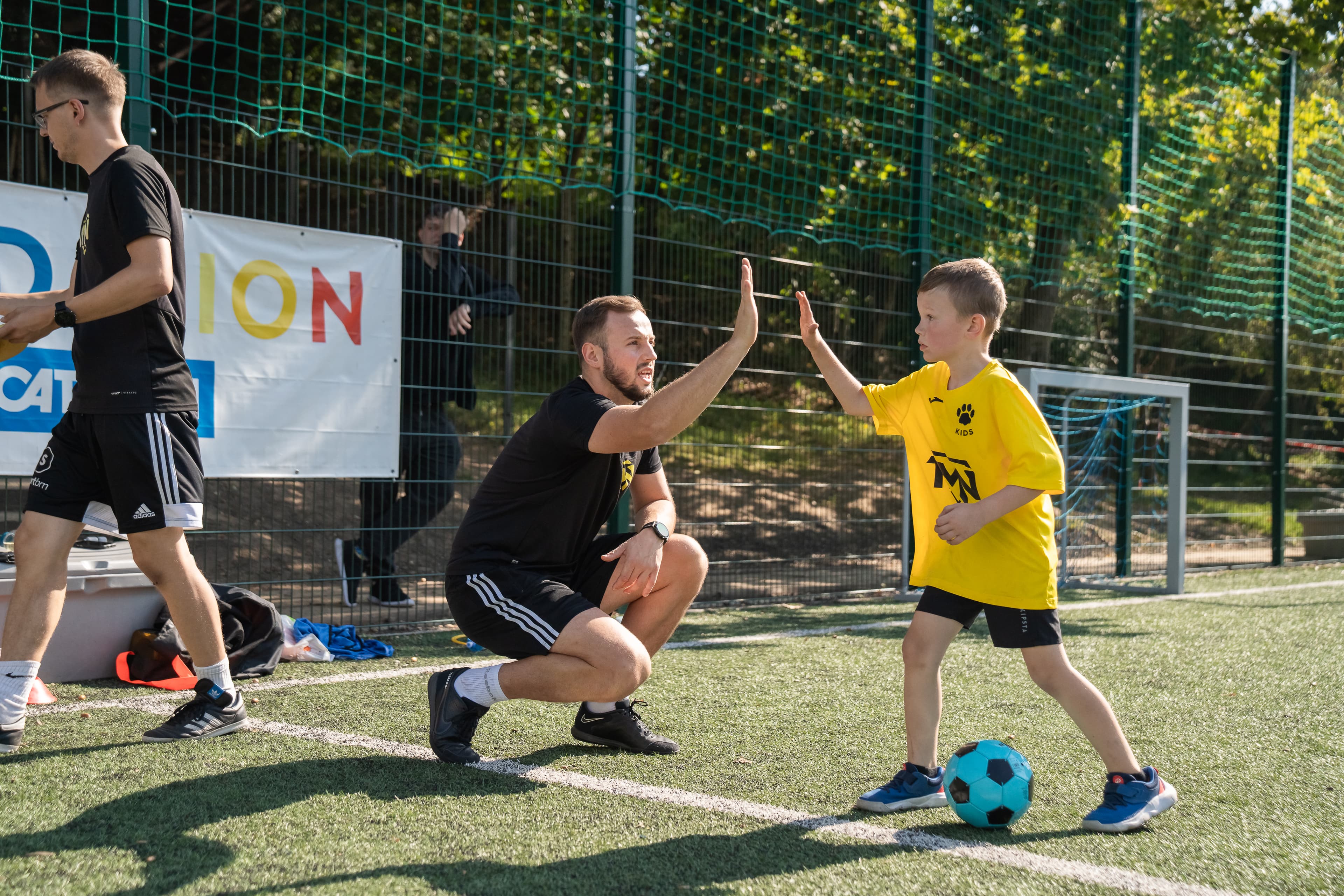 Trener TMN Kids przybija piątkę z dzieckiem po udanym ćwiczeniu